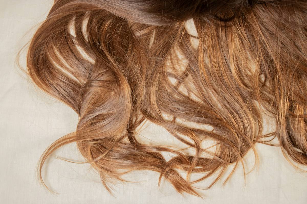 Woman applying frizz free hair conditioner to damp hair in bathroom